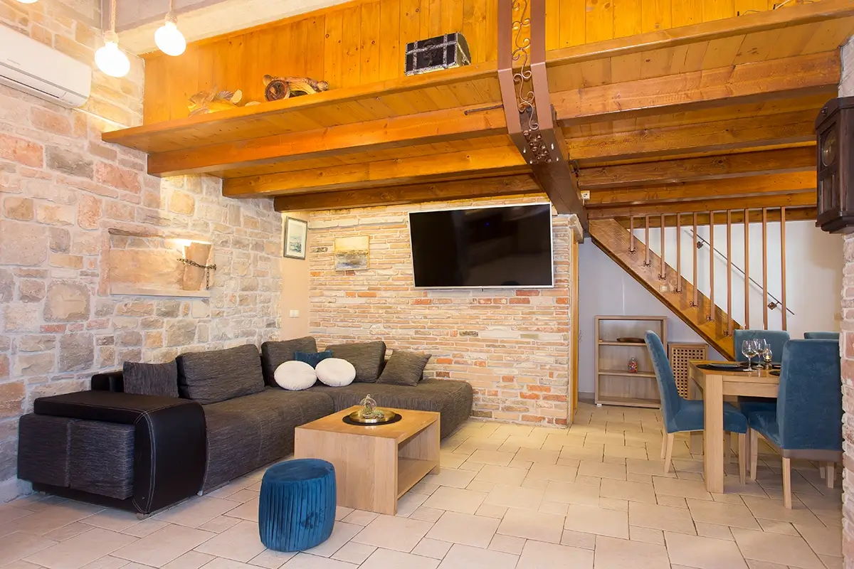 Living room with a stone and wood interior, featuring a large sofa and a television.